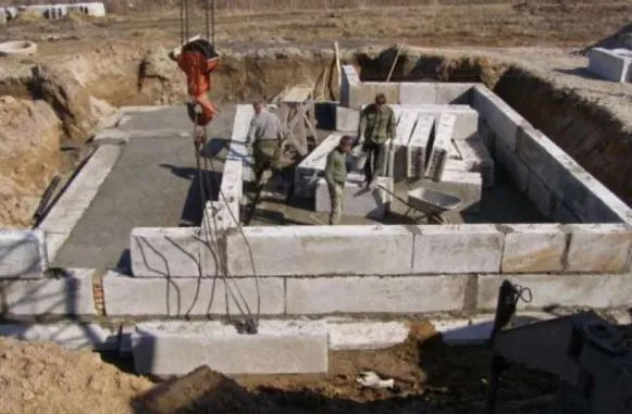 Робітники встановлюють ФБС блоки на стіну