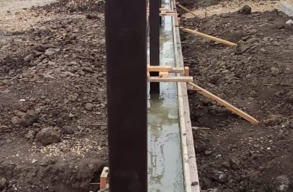 Робітники бетонують фундамент під паркан